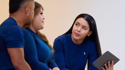 Una empleada de Apple Retail sujeta un iPad mientras habla con dos compa?eros.