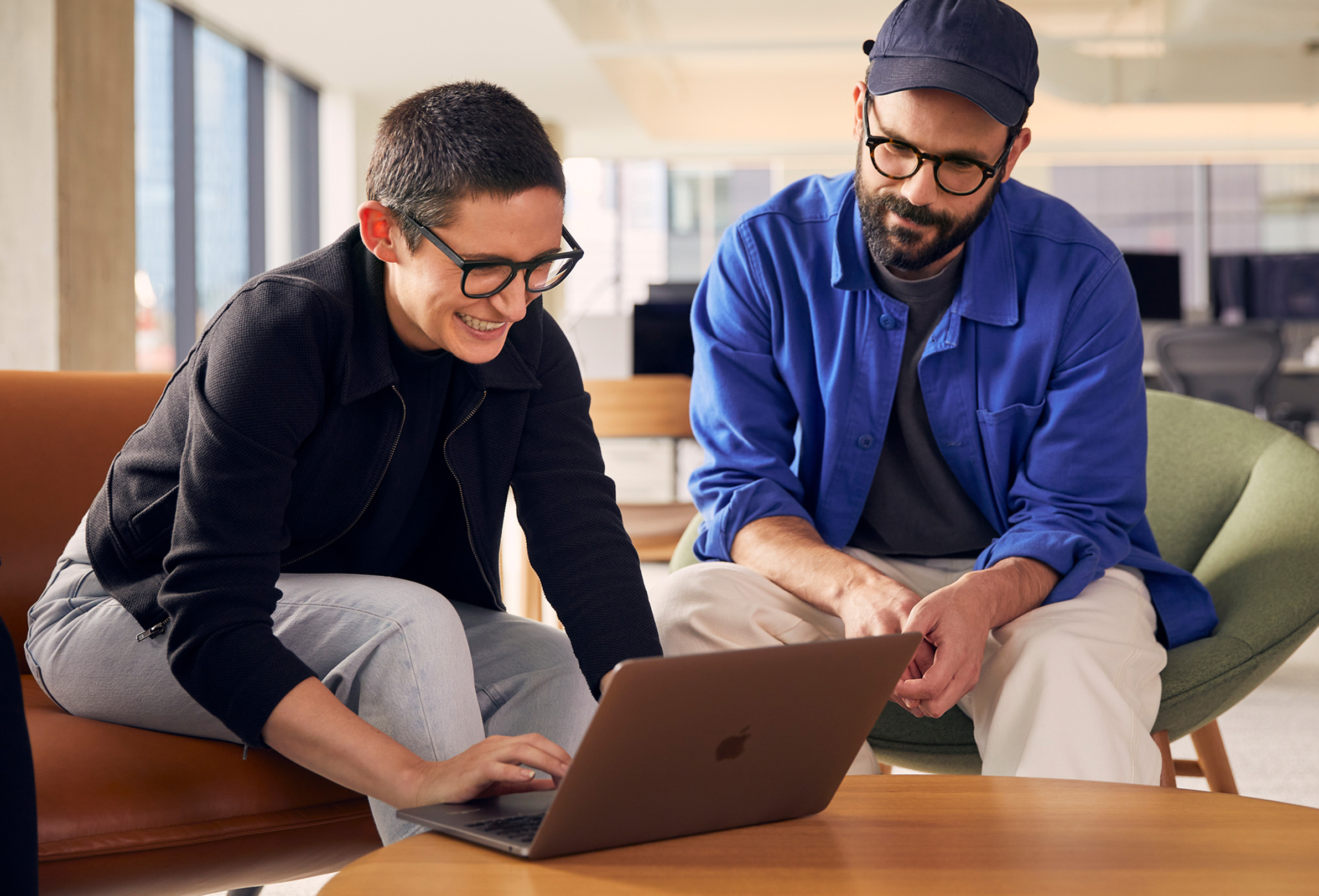 Two Apple employees using a MacBook to collaborate.