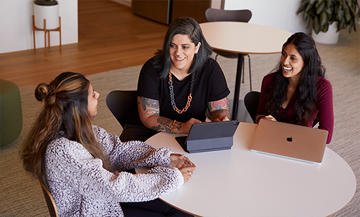 Jo speaking with two colleagues while seated at a small circular table.