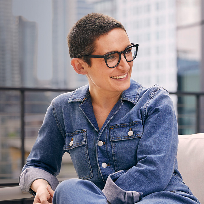 Sophie, seated in front of a cityscape, smiling and looking off to the side.