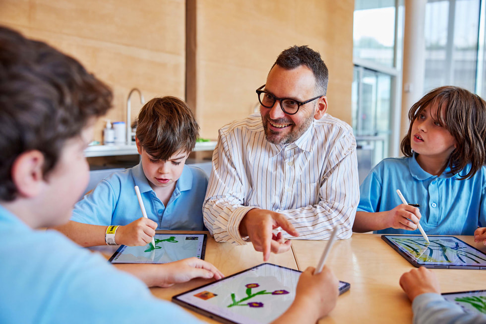 Artist Edward Cutting sits with young artists working with iPad Pro and Apple Pencil.