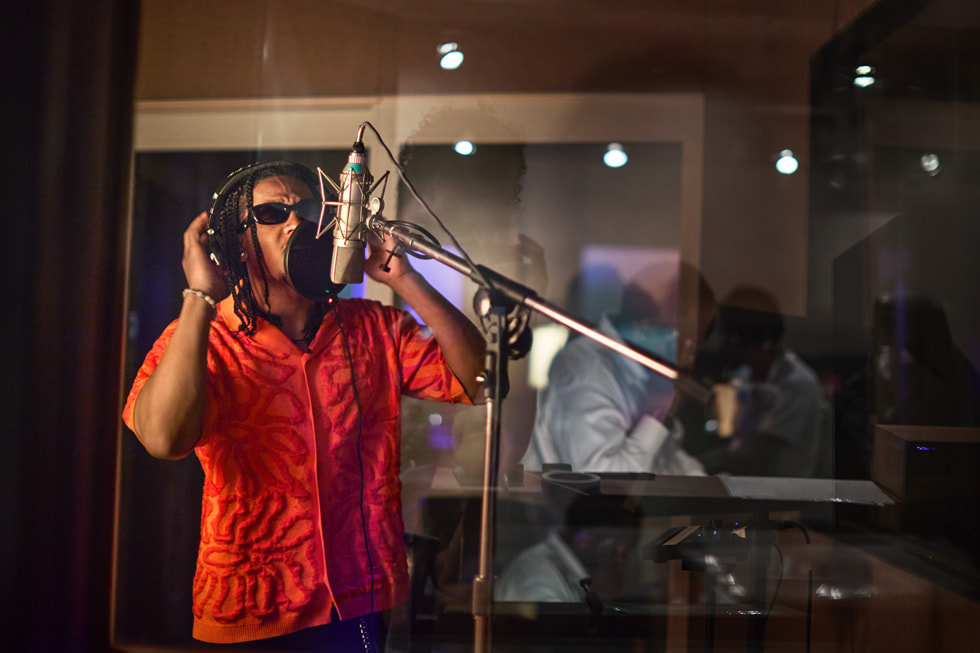 Con audífonos puestos, Emmanuel Strickland canta en un micrófono profesional en un estudio.