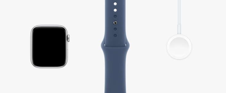 In einer Reihe: Vorderansicht der Apple Watch SE, ein Sportarmband in Polarstern sowie ein magnetisches Ladeger?t auf USB?C Kabel.